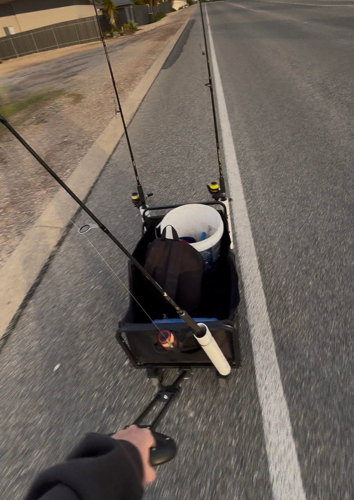Fishing rod and reel setup on a cart by a road